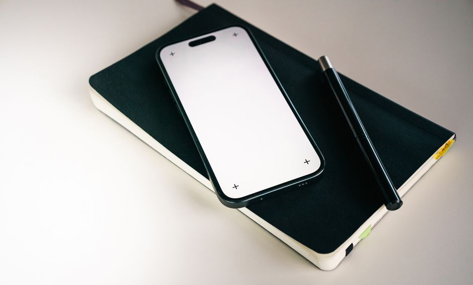 Minimalist flat lay featuring a smartphone, notebook, and pen, ideal for productivity themes.